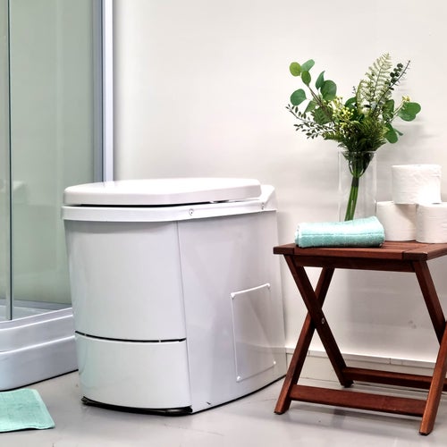 Modernt badrum med förbränningstoalett, duschkabin och liten träpall med tillbehör