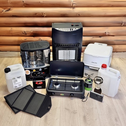 Olika portabla värmare, spisar, dunkar och solpanel placerade på golv framför timmervägg