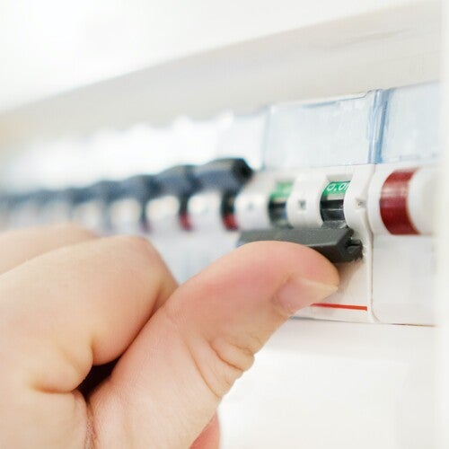 Hand som trycker på en strömbrytare i en elcentral