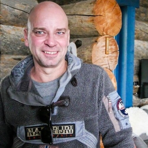 Mika Salminen står inomhus i sin timrade stuga